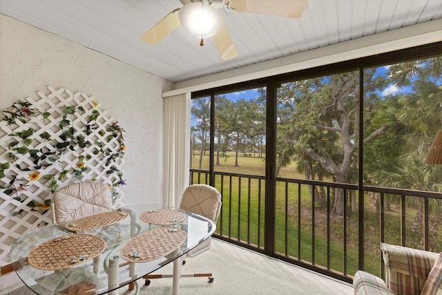 sunroom with carpet, a textured wall, and ceiling fan