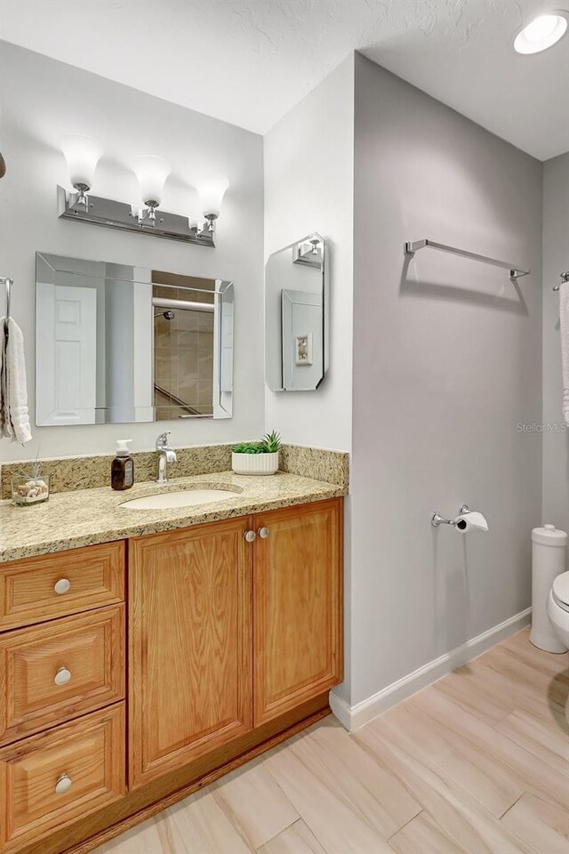 4420 Tecumseh Trl Unit 38, Sarasota, FL 34233 - full bathroom with toilet, tiled shower, vanity, wood finished floors, and baseboards