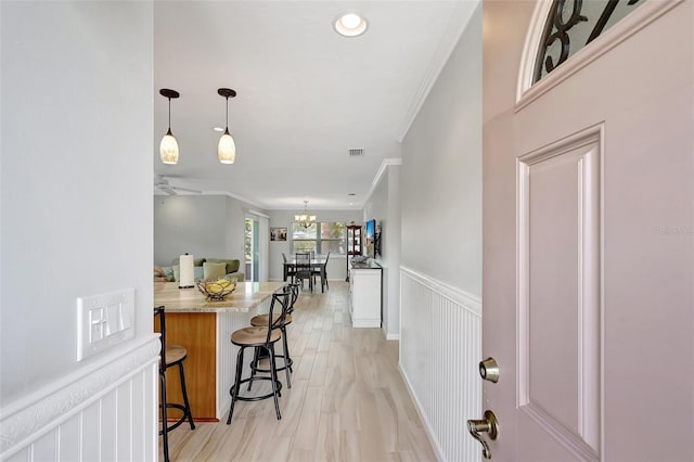 4420 Tecumseh Trl Unit 38, Sarasota, FL 34233 - kitchen with a kitchen breakfast bar, crown molding, a wainscoted wall, decorative light fixtures, and a peninsula