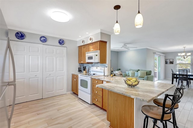 4420 Tecumseh Trl Unit 38, Sarasota, FL 34233 - kitchen with white appliances, a peninsula, light wood-type flooring, ceiling fan, and ornamental molding