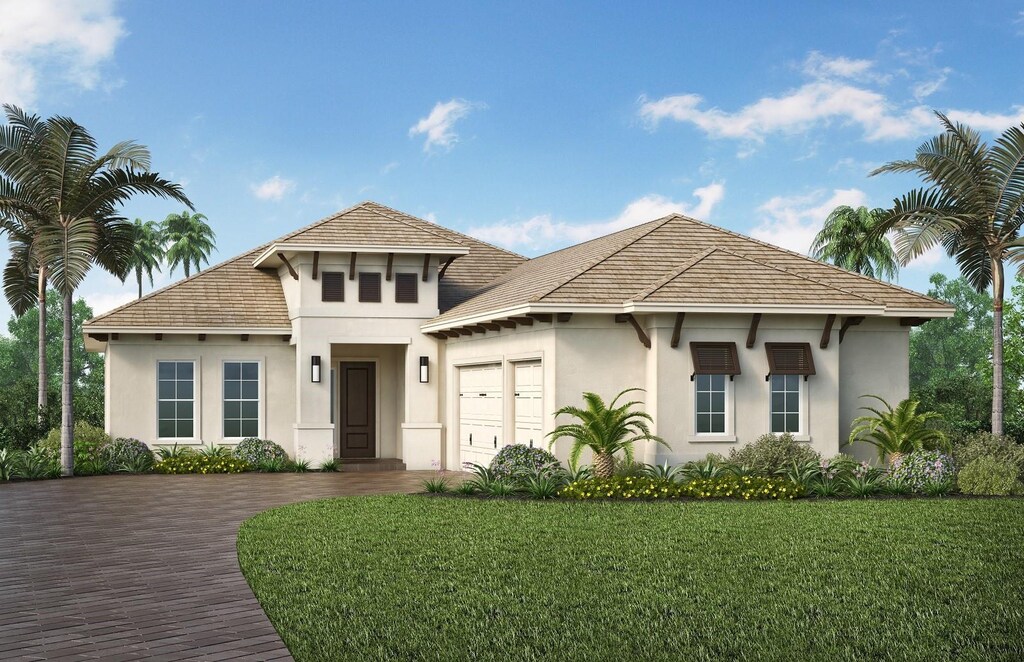 view of front of house featuring stucco siding, an attached garage, a front yard, and decorative driveway