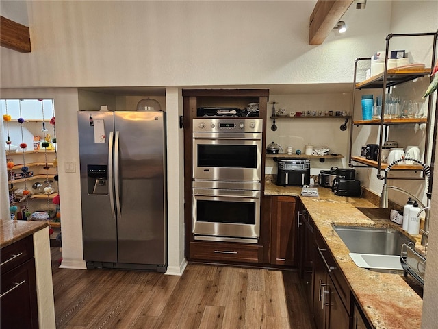 33 Tee View Pl, Rotonda West, FL 33947 - kitchen with appliances with stainless steel finishes, dark wood-style floors, a sink, dark brown cabinets, and light stone counters