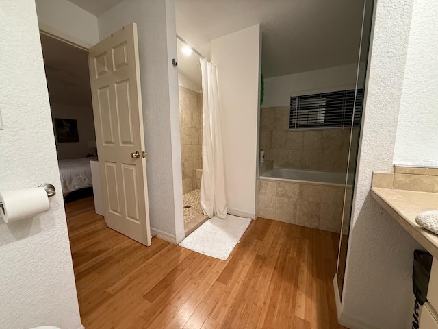 33 Tee View Pl, Rotonda West, FL 33947 - ensuite bathroom with tiled shower, wood finished floors, a bath, and a textured wall