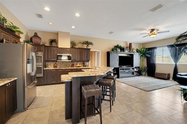 kitchen featuring open floor plan, visible vents, a breakfast bar area, and stainless steel appliances