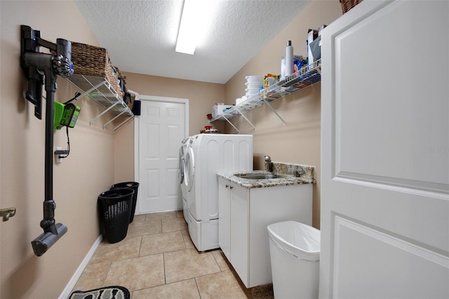 clothes washing area featuring washing machine and clothes dryer, a textured ceiling, laundry area, a sink, and light tile patterned floors