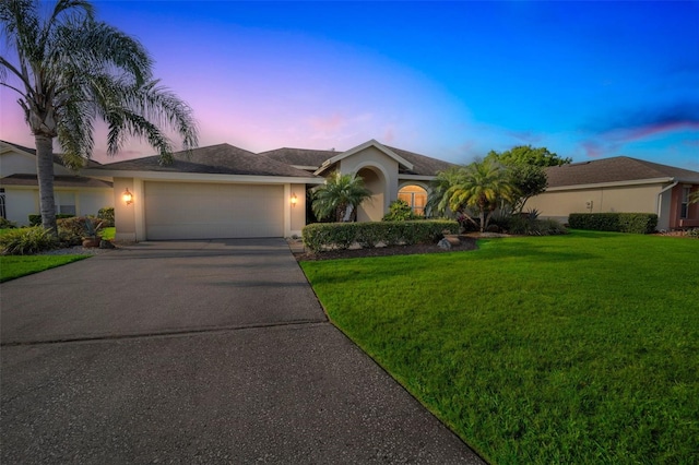 ranch-style home with a garage, a front yard, concrete driveway, and stucco siding
