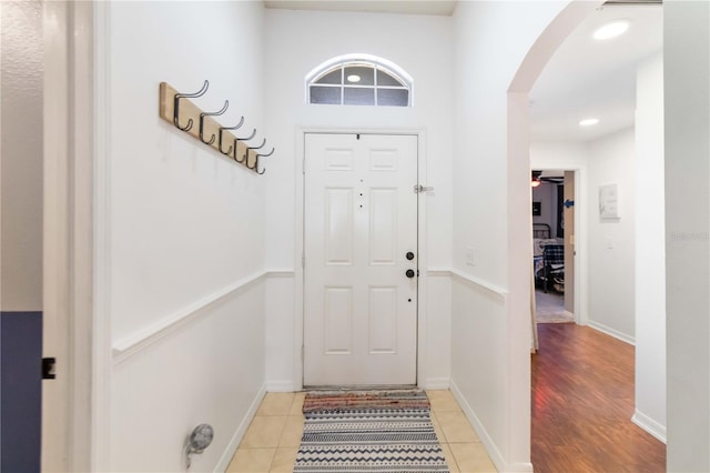 entryway featuring light tile patterned flooring, baseboards, arched walkways, and a ceiling fan