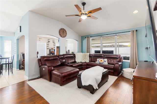 living area featuring lofted ceiling, wood finished floors, arched walkways, and ceiling fan