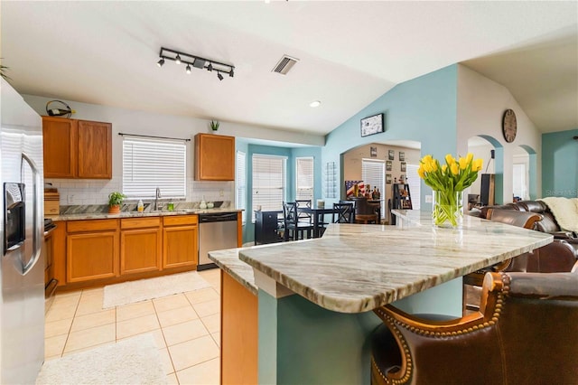 kitchen with a sink, open floor plan, lofted ceiling, stainless steel appliances, and visible vents