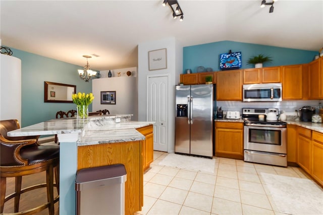 kitchen featuring a chandelier, tasteful backsplash, a center island, light tile patterned floors, and stainless steel appliances
