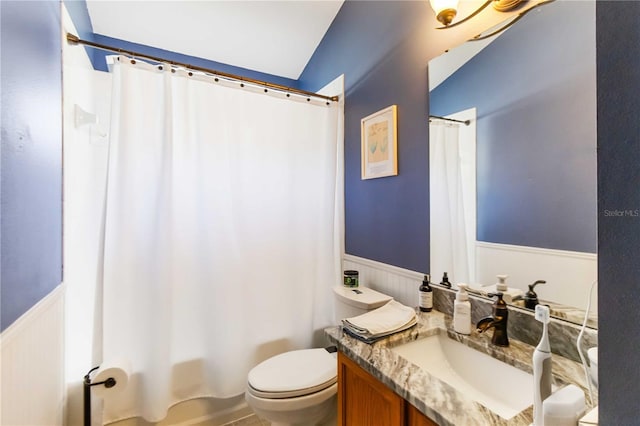 full bathroom featuring a wainscoted wall, toilet, vanity, and shower / bath combination with curtain