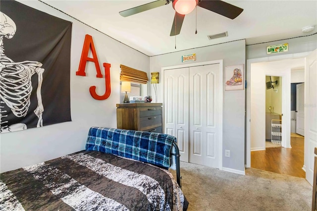 carpeted bedroom with a closet, baseboards, ceiling fan, and visible vents
