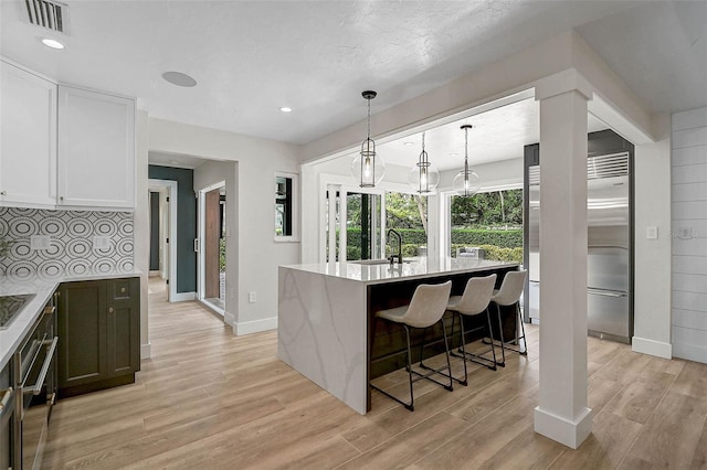 577 Corwood Dr, Sarasota, FL 34234 - kitchen featuring a breakfast bar area, light wood-type flooring, visible vents, white cabinets, and a kitchen island with sink