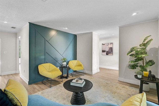 577 Corwood Dr, Sarasota, FL 34234 - living area with a textured ceiling, visible vents, baseboards, ornamental molding, and wood finished floors