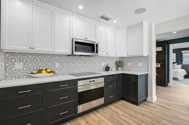 577 Corwood Dr, Sarasota, FL 34234 - kitchen with visible vents, dark cabinetry, white cabinetry, and stainless steel appliances