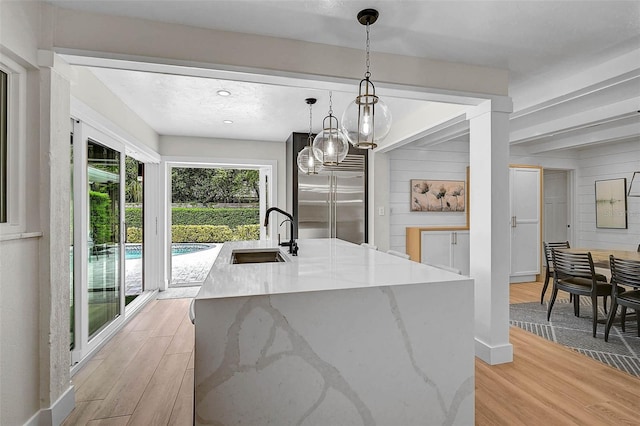 577 Corwood Dr, Sarasota, FL 34234 - kitchen featuring a sink, pendant lighting, light stone countertops, light wood-style flooring, and built in fridge