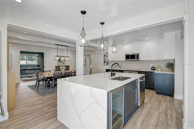 577 Corwood Dr, Sarasota, FL 34234 - kitchen with light wood finished floors, stainless steel microwave, wine cooler, white cabinetry, and a sink
