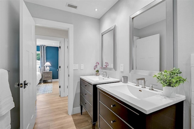 577 Corwood Dr, Sarasota, FL 34234 - ensuite bathroom featuring a sink, two vanities, visible vents, and wood finished floors