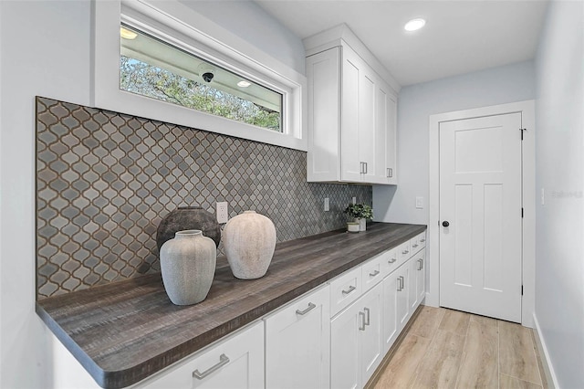 577 Corwood Dr, Sarasota, FL 34234 - kitchen with white cabinets, butcher block counters, light wood finished floors, and decorative backsplash