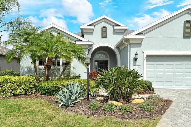 view of front of home with stucco siding, an attached garage, and driveway