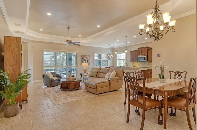 dining area with a raised ceiling, ceiling fan with notable chandelier, visible vents, ornamental molding, and recessed lighting
