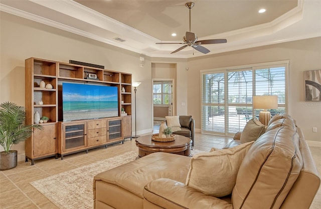 living room featuring a tray ceiling, crown molding, baseboards, visible vents, and a ceiling fan