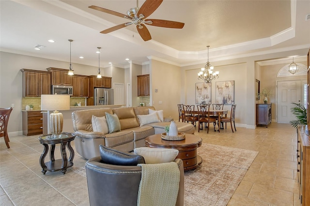 living room featuring baseboards, a tray ceiling, ceiling fan with notable chandelier, and ornamental molding