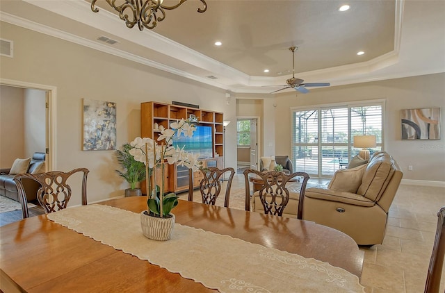 dining room with a tray ceiling, visible vents, and crown molding
