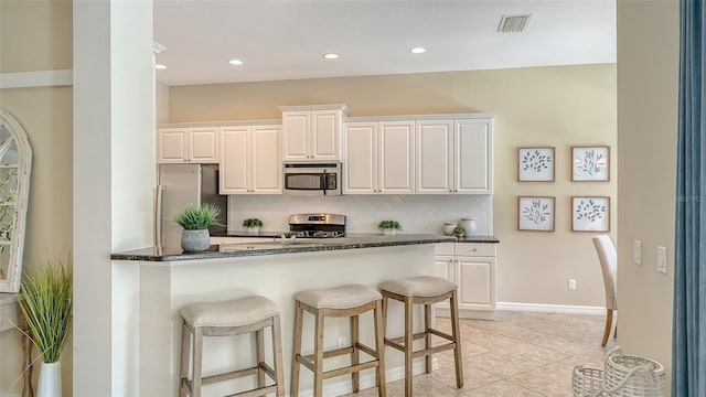 12041 Thornhill Ct, Lakewood Ranch, FL 34202 - kitchen with white cabinets, visible vents, appliances with stainless steel finishes, a breakfast bar area, and backsplash