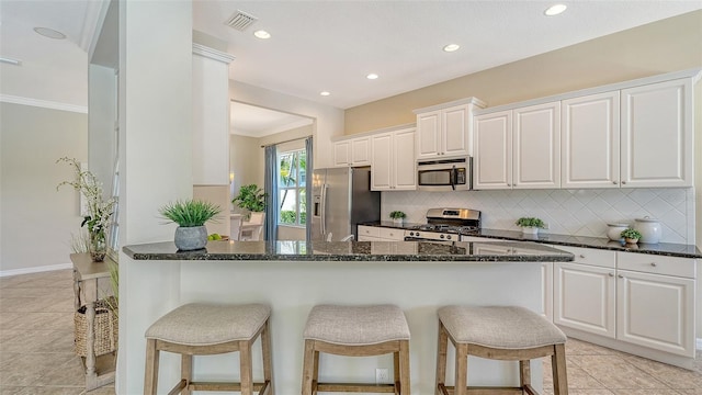 12041 Thornhill Ct, Lakewood Ranch, FL 34202 - kitchen featuring stainless steel appliances, white cabinets, a kitchen bar, and decorative backsplash