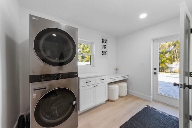 washroom with cabinet space, light wood-style floors, recessed lighting, baseboards, and stacked washer and clothes dryer