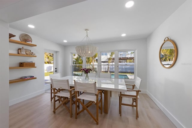 dining space with recessed lighting, baseboards, a notable chandelier, and light wood-type flooring