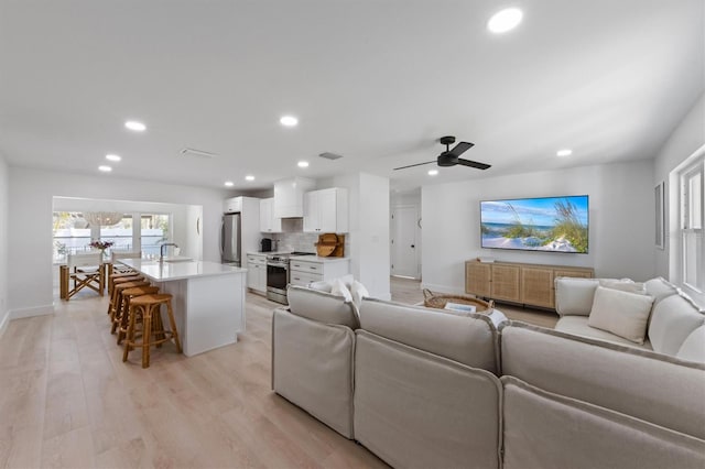 living area featuring baseboards, light wood-type flooring, recessed lighting, and visible vents