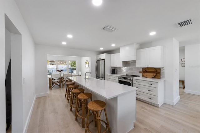 kitchen with baseboards, appliances with stainless steel finishes, visible vents, and a kitchen bar