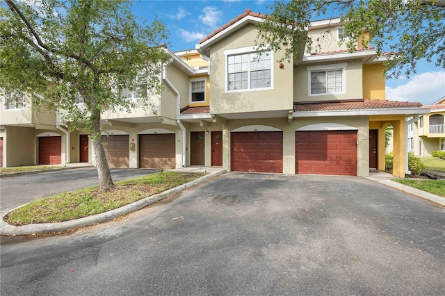 view of front of home featuring a tile roof, stucco siding, driveway, and a garage