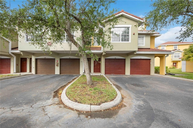 mediterranean / spanish house with driveway, stucco siding, a tiled roof, and a garage