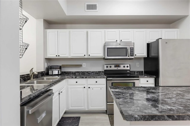 kitchen with white cabinetry, appliances with stainless steel finishes, visible vents, and a sink