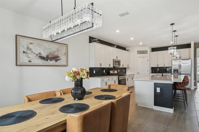 15104 Blue Bay Ter, Lakewood Ranch, FL 34211 - kitchen featuring stainless steel appliances, a sink, decorative backsplash, a kitchen bar, and white cabinetry