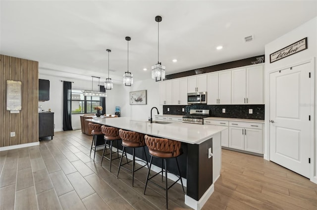 15104 Blue Bay Ter, Lakewood Ranch, FL 34211 - kitchen featuring stainless steel appliances, backsplash, a sink, light countertops, and a kitchen breakfast bar