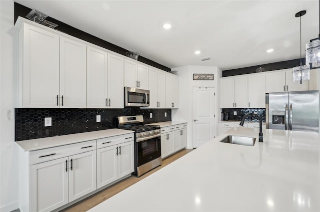 15104 Blue Bay Ter, Lakewood Ranch, FL 34211 - kitchen featuring appliances with stainless steel finishes, a sink, light countertops, backsplash, and hanging light fixtures