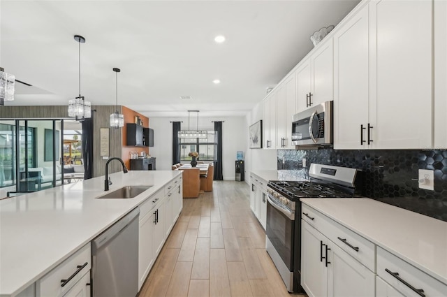 15104 Blue Bay Ter, Lakewood Ranch, FL 34211 - kitchen with stainless steel appliances, a sink, light countertops, backsplash, and white cabinets