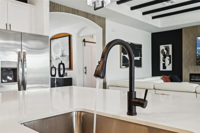 15104 Blue Bay Ter, Lakewood Ranch, FL 34211 - kitchen view of stainless steel fridge with ice dispenser, arched walkways, white cabinetry, a sink, and light countertops