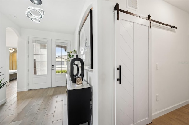 15104 Blue Bay Ter, Lakewood Ranch, FL 34211 - entryway with arched walkways, a barn door, light wood-style flooring, baseboards, and a chandelier