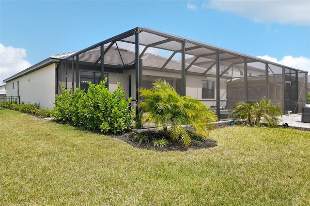 15104 Blue Bay Ter, Lakewood Ranch, FL 34211 - rear view of property featuring a yard, stucco siding, glass enclosure, and central air condition unit