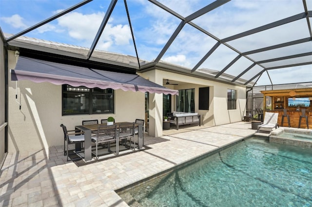 15104 Blue Bay Ter, Lakewood Ranch, FL 34211 - rear view of house with stucco siding, a patio, outdoor dining area, a pool with connected hot tub, and glass enclosure