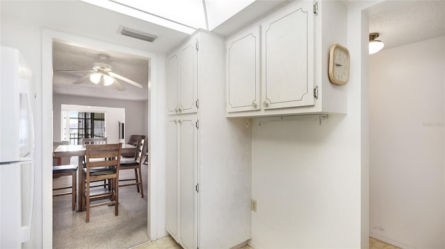 3763 Lake Bayshore Dr Unit 310, Bradenton, FL 34205 - kitchen with a ceiling fan, light carpet, white cabinetry, white refrigerator, and visible vents