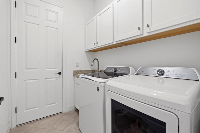 clothes washing area with separate washer and dryer, light tile patterned flooring, cabinet space, and baseboards