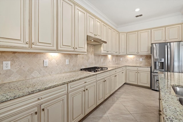 kitchen featuring cream cabinets, stainless steel appliances, under cabinet range hood, decorative backsplash, and light tile patterned floors