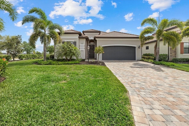 mediterranean / spanish-style home with an attached garage, decorative driveway, stucco siding, a front lawn, and a tile roof