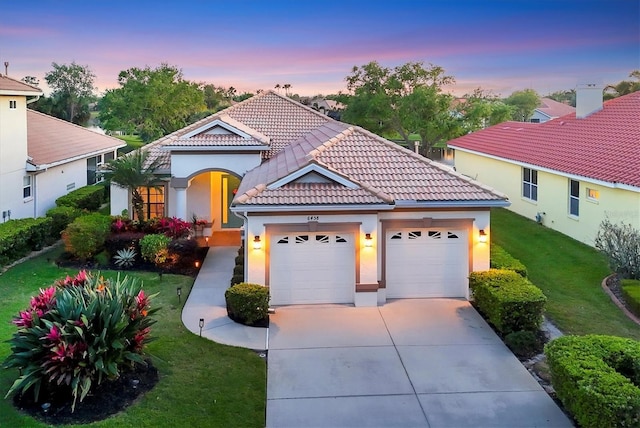 mediterranean / spanish house with a tiled roof, stucco siding, a front lawn, an attached garage, and driveway